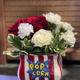 Red and white roses arranged in a popcorn bucket-shaped container