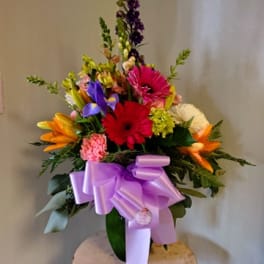 Colorful mixed flower arrangement with a lavender bow in a vase