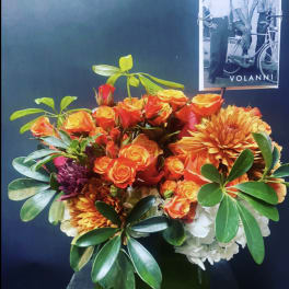 Orange roses and chrysanthemums arranged in a square glass vase