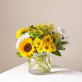 Yellow and white flowers arranged in a clear glass vase