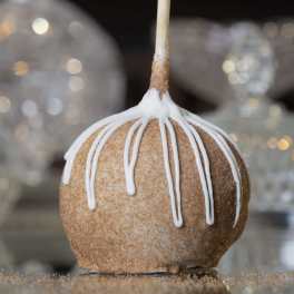 Caramel apple with white icing drizzle on a stick