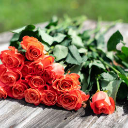 Bundle of coral-orange roses lying on a wooden surface