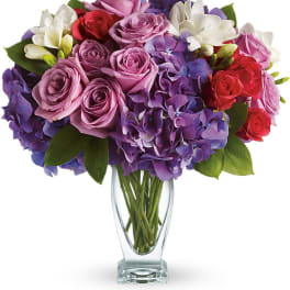 Bouquet of pink, purple, red, and white flowers in a clear glass vase