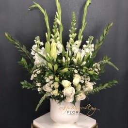 White floral arrangement in a white vase with tall green stems