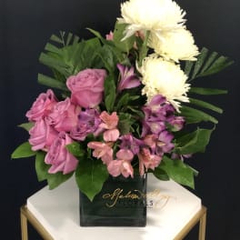Pink roses and purple flowers in a black vase with white blooms