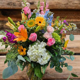 Colorful mixed bouquet in a glass vase with roses, lilies, hydrangea, and gerbera daisies
