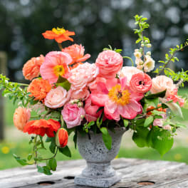Pink and coral flower arrangement in a gray urn vase
