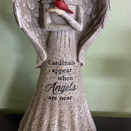 Angel figurine holding a red cardinal with text on the base