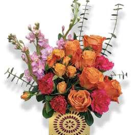 Orange roses and pink flowers in a decorative yellow vase