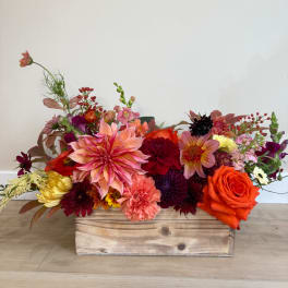Mixed flower arrangement in a wooden box with orange and pink blooms