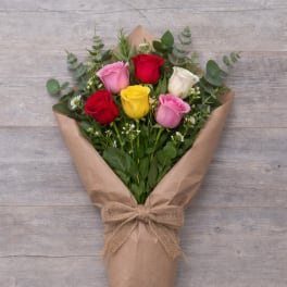 Bouquet of multicolored roses wrapped in brown paper with a burlap bow