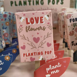Pink plant marker with hearts and the words "Love flowers"
