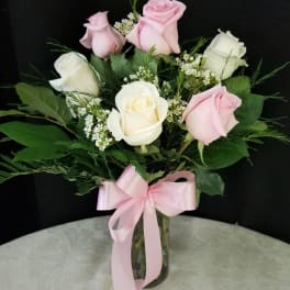 Pink and white roses in a glass vase with a pink ribbon