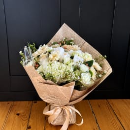 Wrapped bouquet of white and cream flowers tied with a satin ribbon