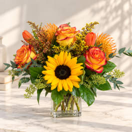 Sunflower and orange rose bouquet in a clear glass vase