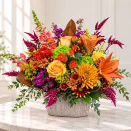Colorful mixed flower arrangement in a textured white container