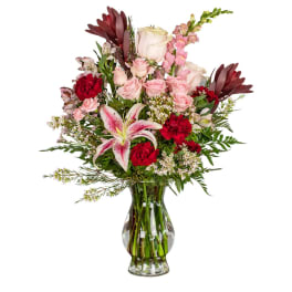 Mixed bouquet of pink and red flowers in a clear glass vase