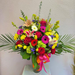 Colorful mixed bouquet in a clear glass vase with ribbon