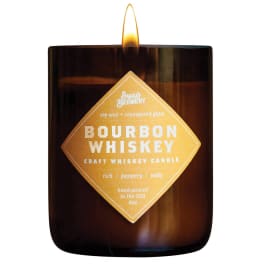 Brown glass candle with lit flame and a gold label reading Bourbon Whiskey Craft Whiskey Candle