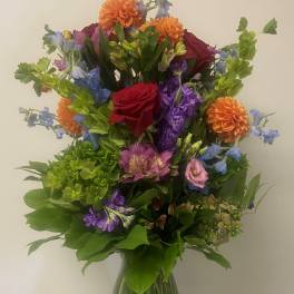Mixed bouquet in a glass vase with red, orange, purple, and blue flowers