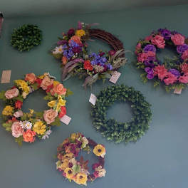 Wall display of colorful floral wreaths and greenery rings