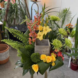 Tropical floral arrangement with yellow roses and green blooms in a wooden box