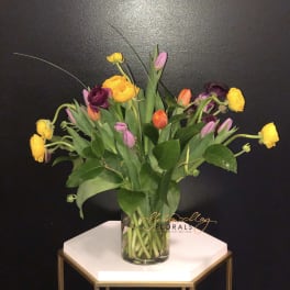 Colorful tulips in a clear glass vase on a small table