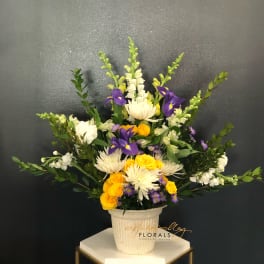 Mixed bouquet in a white pot with yellow, white, and purple flowers