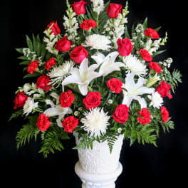 Red roses and white lilies in a white pedestal vase