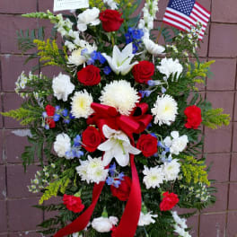 Standing floral spray with red roses, white lilies, and an American flag