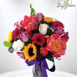 Colorful mixed bouquet in a glass vase with a purple ribbon