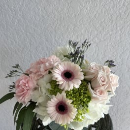 Pink gerbera daisies, roses, and carnations in a low bouquet