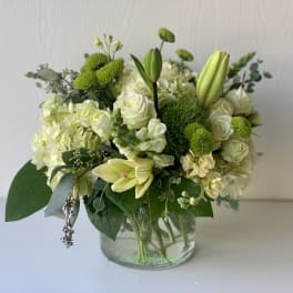 White and green floral arrangement in a clear glass vase