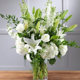 White lilies, roses, and hydrangeas in a clear glass vase
