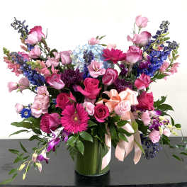 Large mixed bouquet of pink, purple, and blue flowers in a glass vase