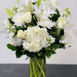 White lilies and roses arranged in a clear glass vase