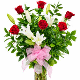 Bouquet of red roses and white lilies in a glass vase with a pink bow