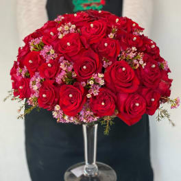 Red rose bouquet with pink filler flowers in a clear glass vase