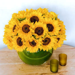 Sunflower bouquet in a green glass vase with two small votive holders