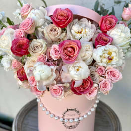 Pink and white roses arranged in a pastel pink hat box