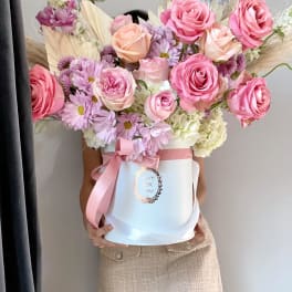 Large bouquet of pink roses and lavender daisies in a white hat box