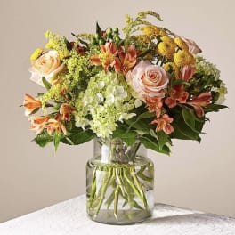 Mixed bouquet of roses, hydrangeas, and orange lilies in a glass vase
