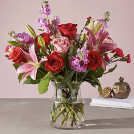 Mixed bouquet of red and pink flowers in a clear glass vase