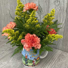 Pink carnations and yellow filler flowers in a decorated mug