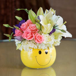 Pink roses and white lilies in a yellow smiley-face vase