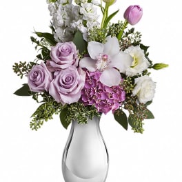 Lavender roses, white orchids, and pink tulips in a glass vase