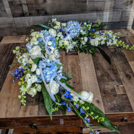 Long blue and white floral spray with ribbons arranged on a wooden surface