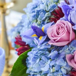 Close-up bouquet of blue hydrangeas, pink roses, and purple irises