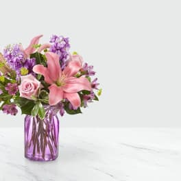 Pink lilies and roses in a purple glass vase