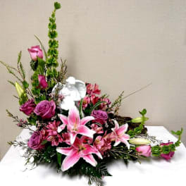 Pink lilies and roses arranged with a white angel figurine